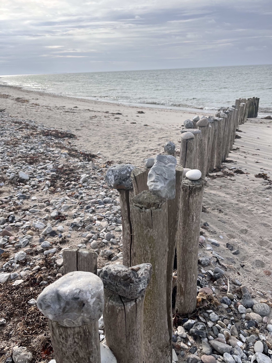 Sten på træstolper, der viser en vej langs stranden